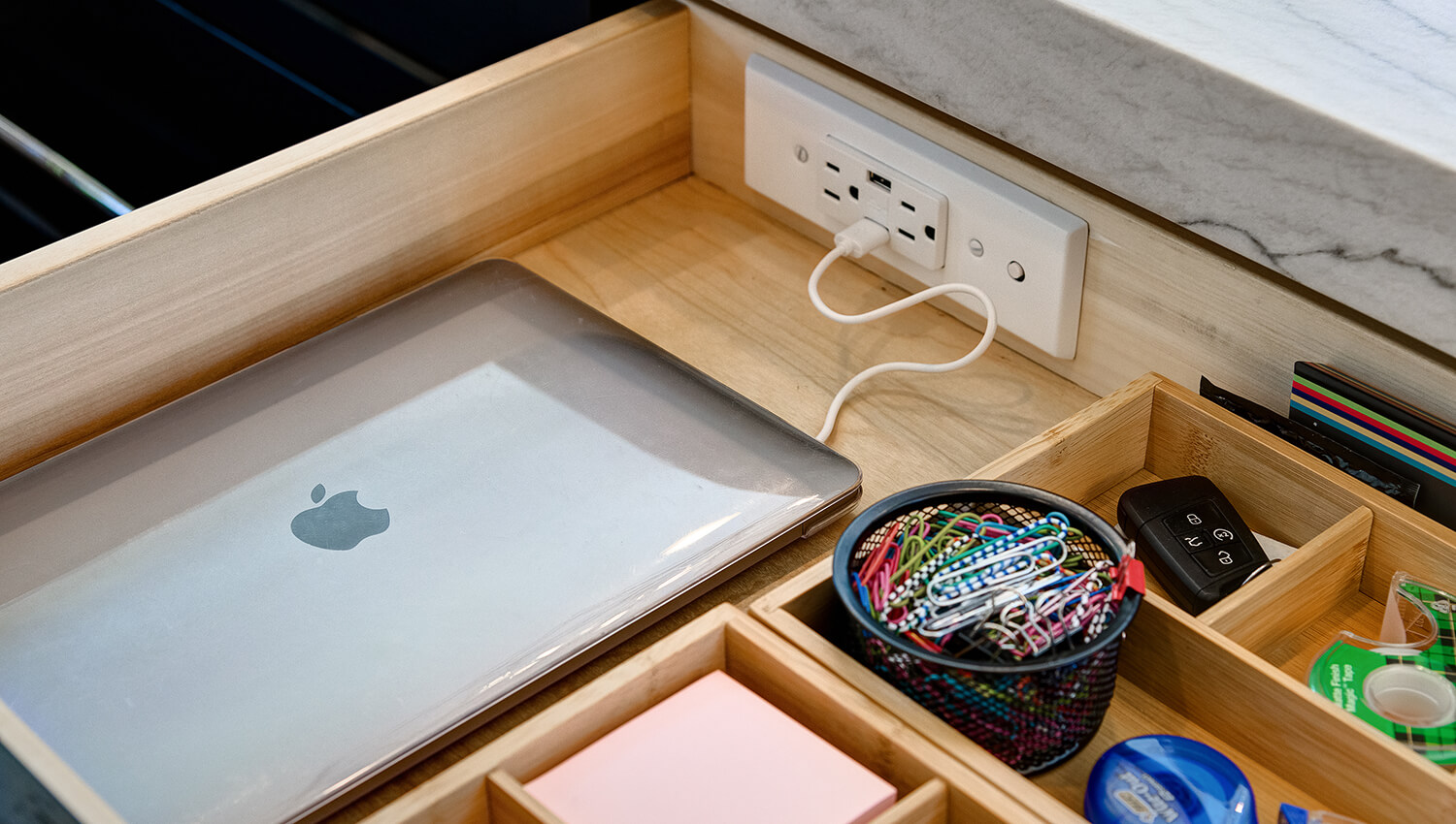 A kitchen drawer can be outfitted with a charging station and dividers for organized storage for homework supplies and devices.