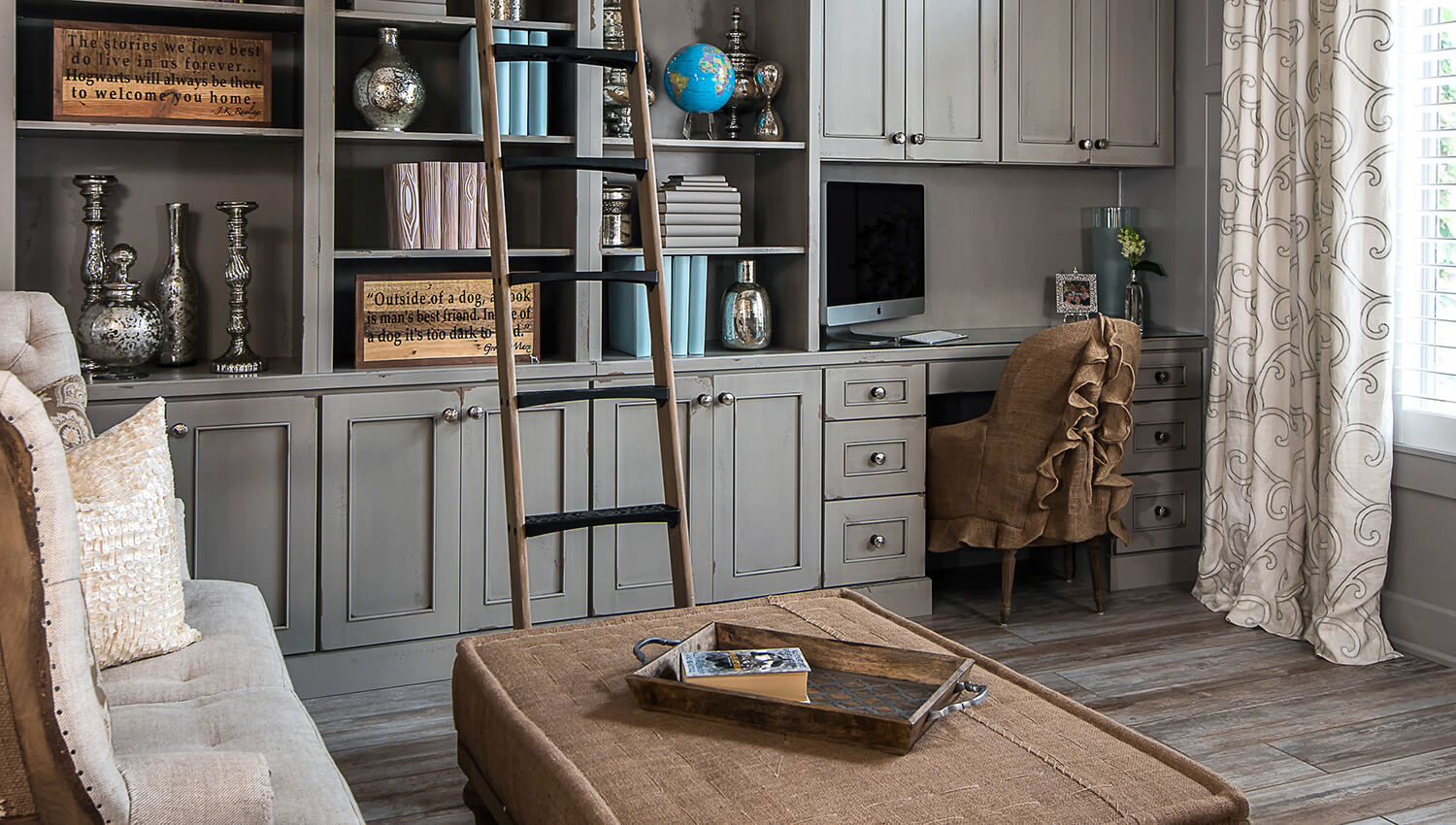 A multi-functional living room with a home library wall with an integrated home office design with shabby chic styled bookcases.