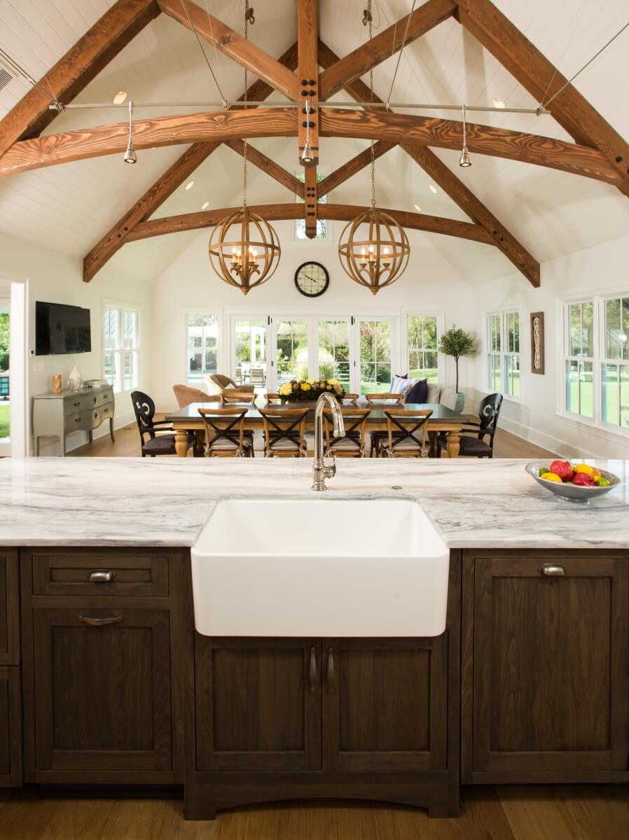 Commanding rustic beams and the farmhouse sink are so appropriate for this space