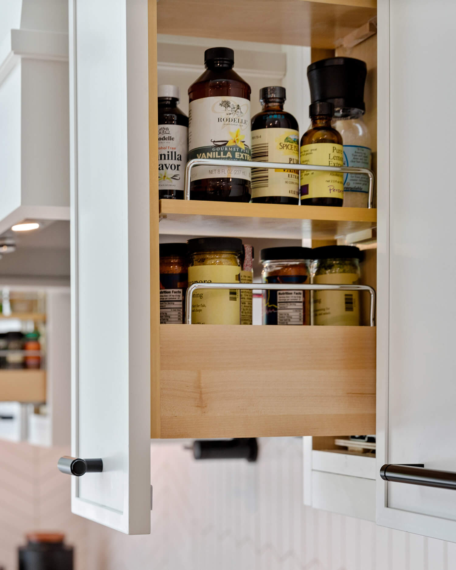 Cabinet storage accessories like a thin pull-out wall cabinet spice rack keep seasonings organized and within easy reach of the kitchen prep zone. Integrated into custom kitchen cabinets, this space-saving storage solution maximizes accessibility while reducing countertop clutter.