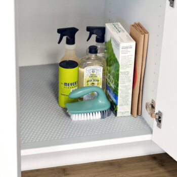 A storage idea for under the kitchen sink that protects the cabinet from water damage and moisture using a sink base mat.