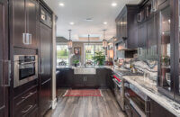 A dark kitchen with black stained cherry cabinets from Dura Supreme Cabinetry and beautiful black and white granite countertops.