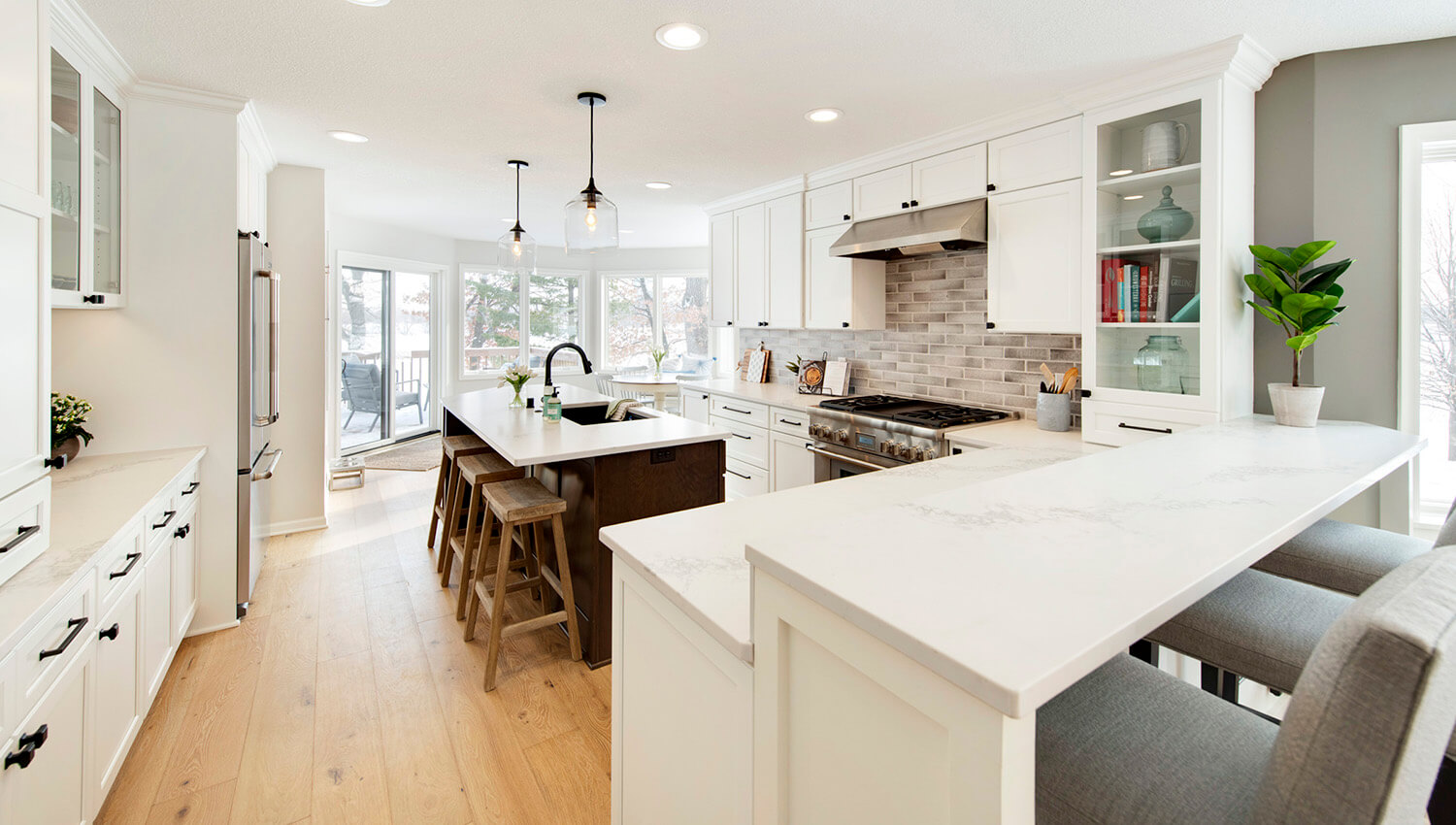 This large kitchen design features a kitchen island and a kitchen peninsula both with car stool seating.