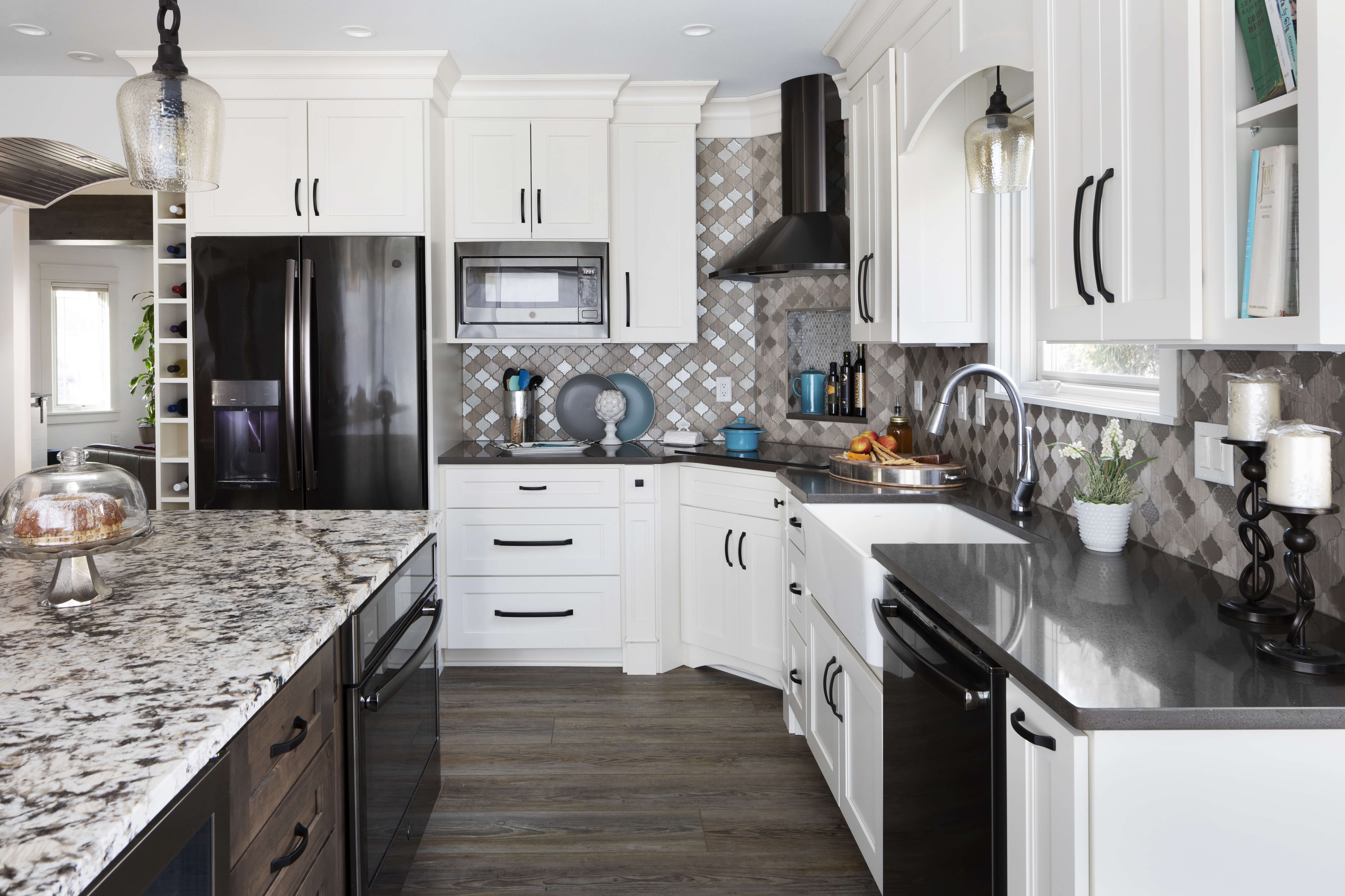 A kitchen remodel with a combination of white painted cabinets and a gray stained kitchen island featuring black countertops and black staineless steel appliances.