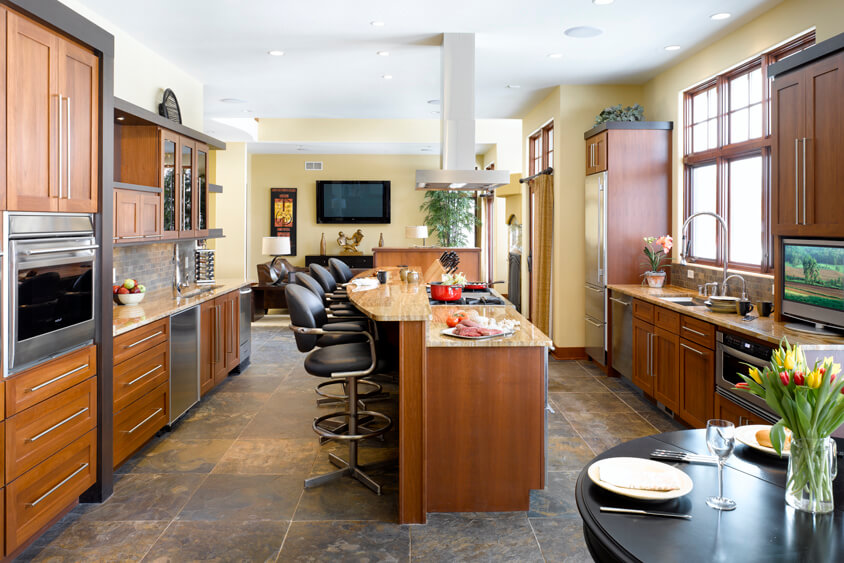 A warm stained contemporary ktichen with a long kitchen island with a cooktop and bar height seating.