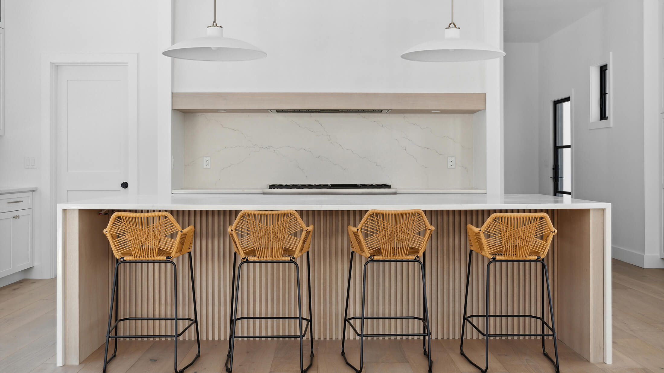 Counter height bar stool seating at a beautiful modern farmhouse kitchen island across from a large kitchen alcove work station featuring Dura Supreme Cabinetry.