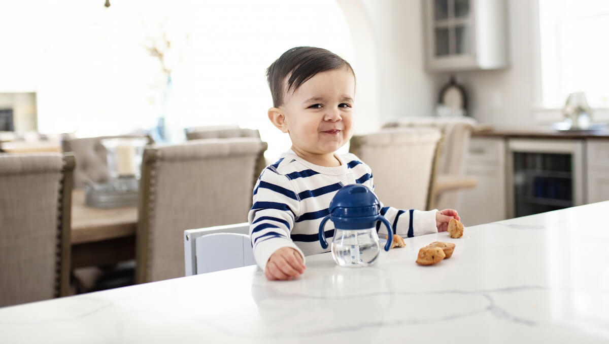 An adorable toddler sitting at a bar stool eating at a kitchen island with countertop height seating.