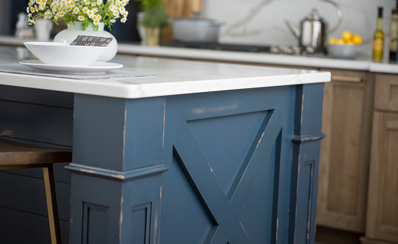 The end of this modern farmhouse kitchen island has an X-shaped detail and decorative columns to create the look of a grand piece of furniture.