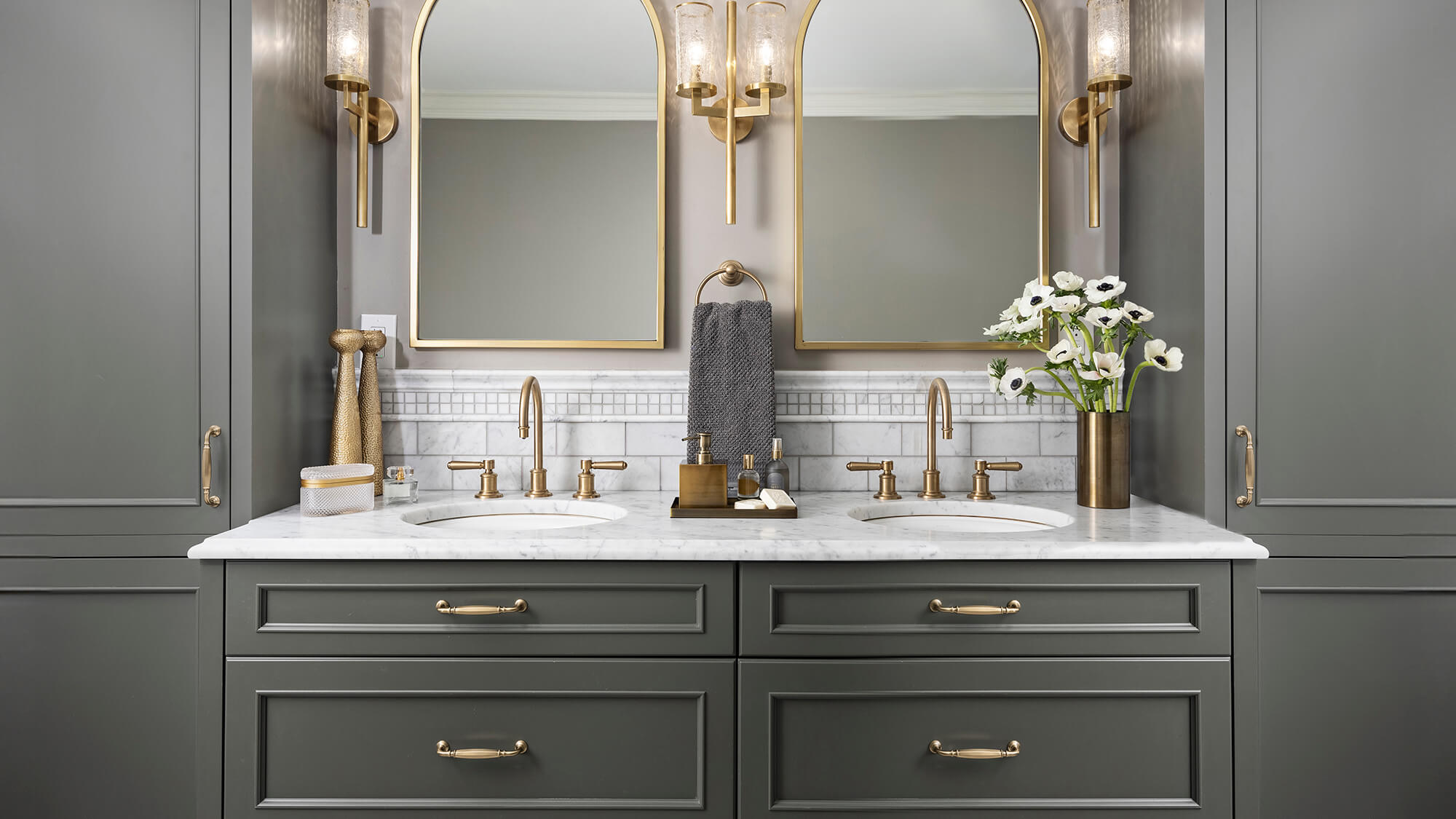 Dark green cabinets in a moody bathroom design.