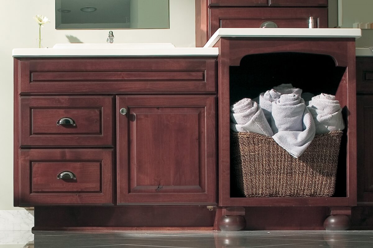 An open cabinet in a bathroom vanity with storage for towels or a laundry basket.