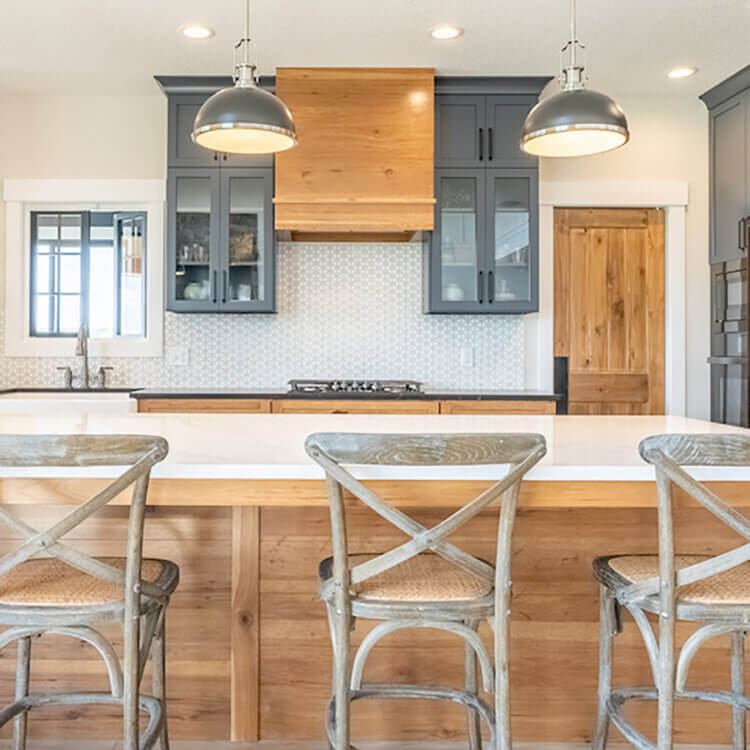 The story of a model home with an impressive kitchen design that's on-trend. The cabinetry combines dark gray painted cabinets and warm toast stained hickory cabinetry for a unique look.