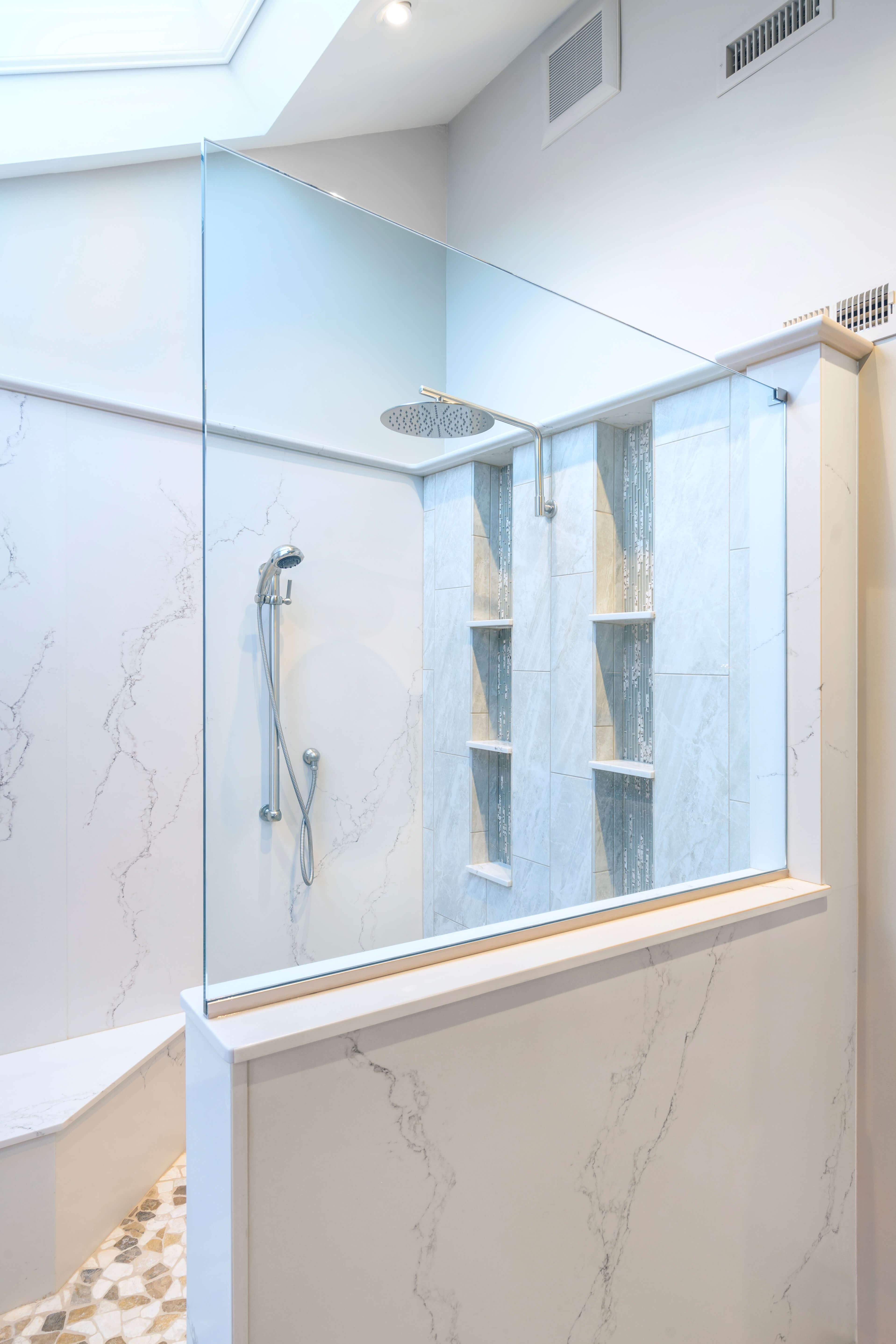 A tiled Shower with a glass wall.