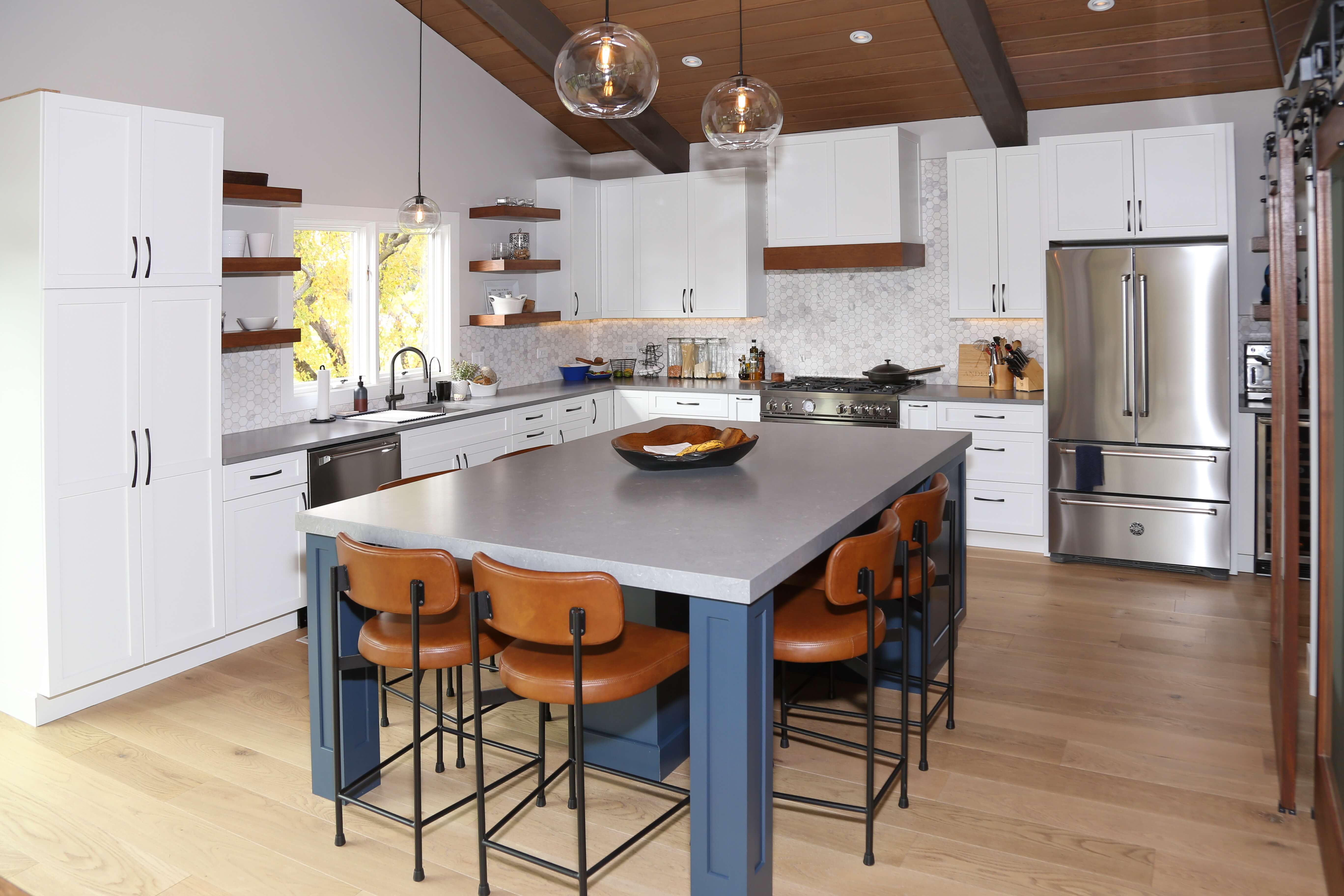 A modern farmhouse kitchen with a navy blue painted kitchen island with countertop seating for six.