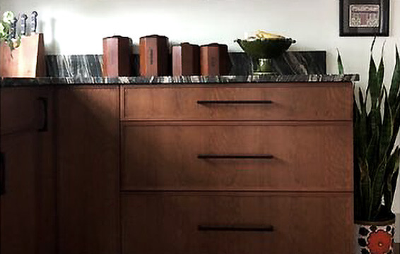 A close up of cherry kitchen cabinets with a warm, medium brown stain and a skinny shaker door style.