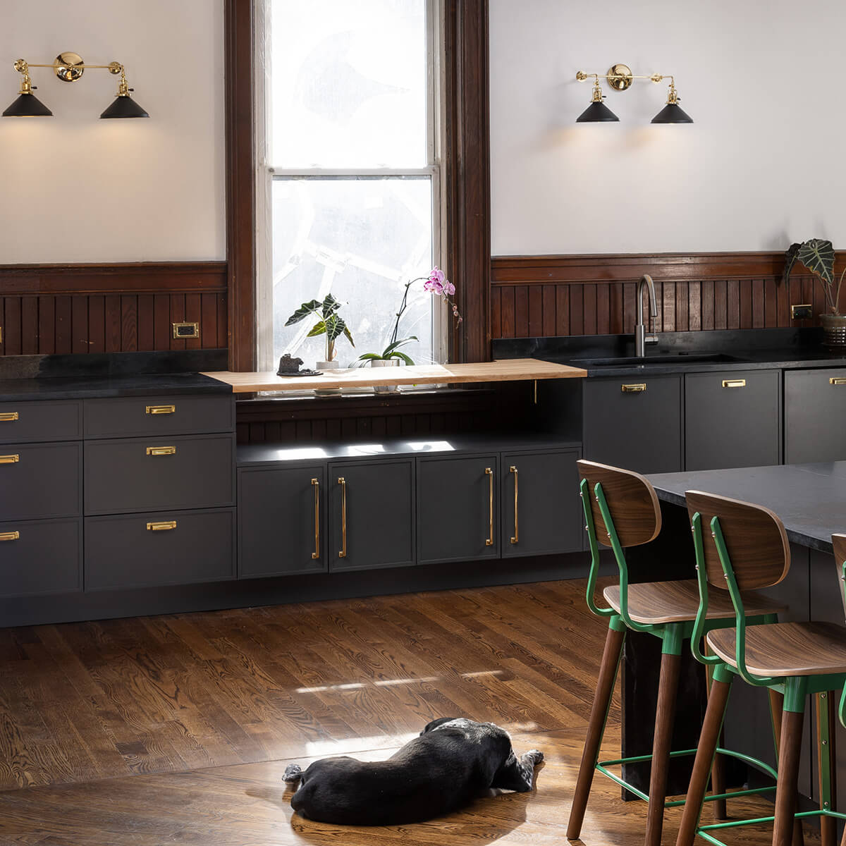 A modern kitchen with black painted cabinets that have a modern shaker cabinet door style.