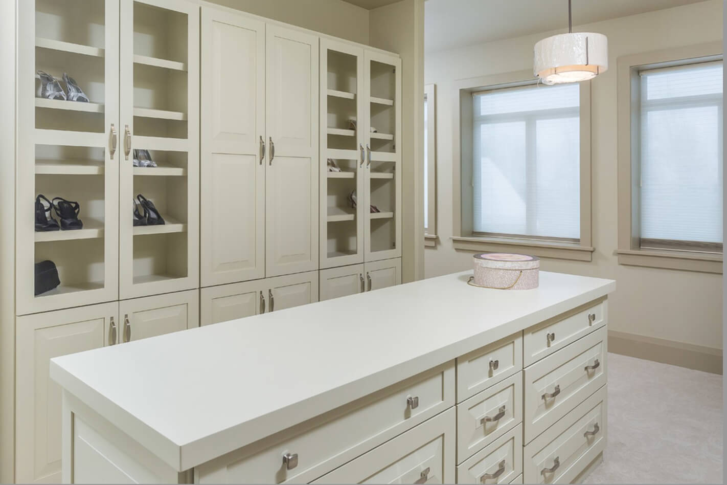 A walk-in closet with a wall of cabinetry with shelving for shoes and a long, skinny island.