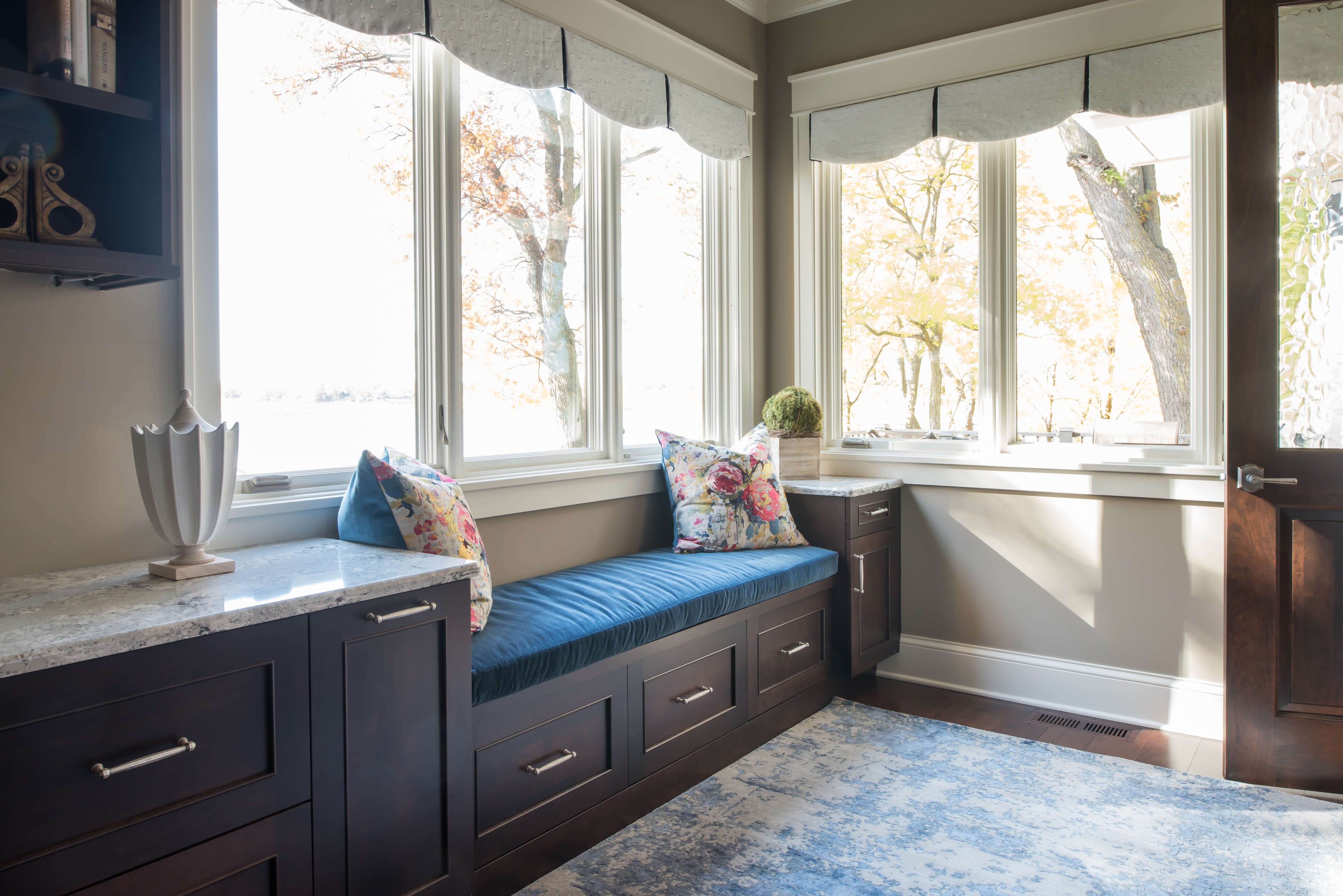 An entryway with a boot bench under a window with a dark finish.