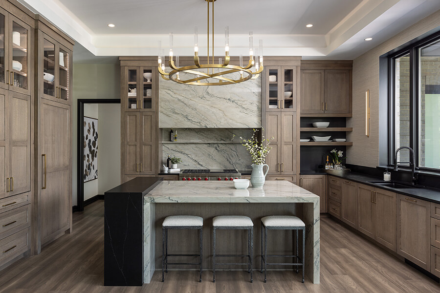 A modern farmhouse with transitional styled cabinets in a medium brown stain and a sleek quartz hood and waterfall kitchen island.
