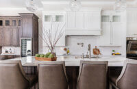 A transitional and casual kitchen design with elegant finishes. A grand white painted wood hood takes center stage over the knotty alder kitchen island.