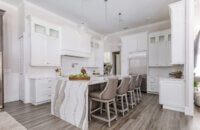 A luxurious kitchen design with white painted cabinets and a knotty alder kitchen island with a waterfall countertop.