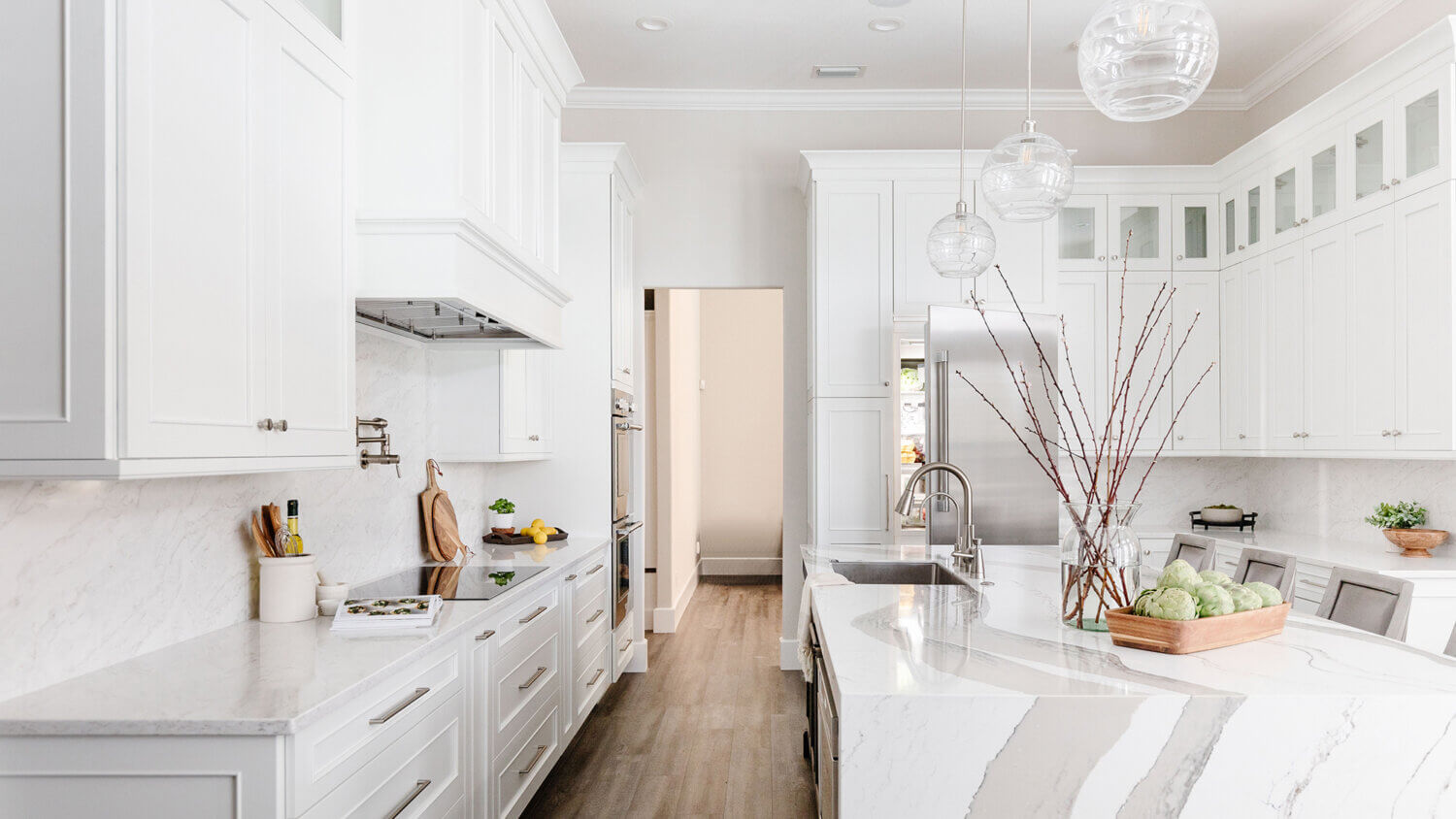 A luxurious white painted kitchen with a classic flat panel door style and custom cabinet details.