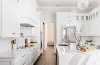 A luxurious white painted kitchen with a classic flat panel door style and custom cabinet details.