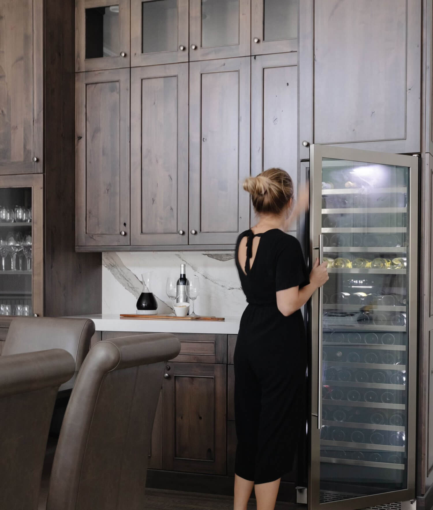 The beverage center wall of knotty alder cabinets in the dining room featuring a tall wine fridge and lots of storage.