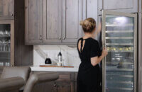 The beverage center wall of knotty alder cabinets in the dining room featuring a tall wine fridge and lots of storage.