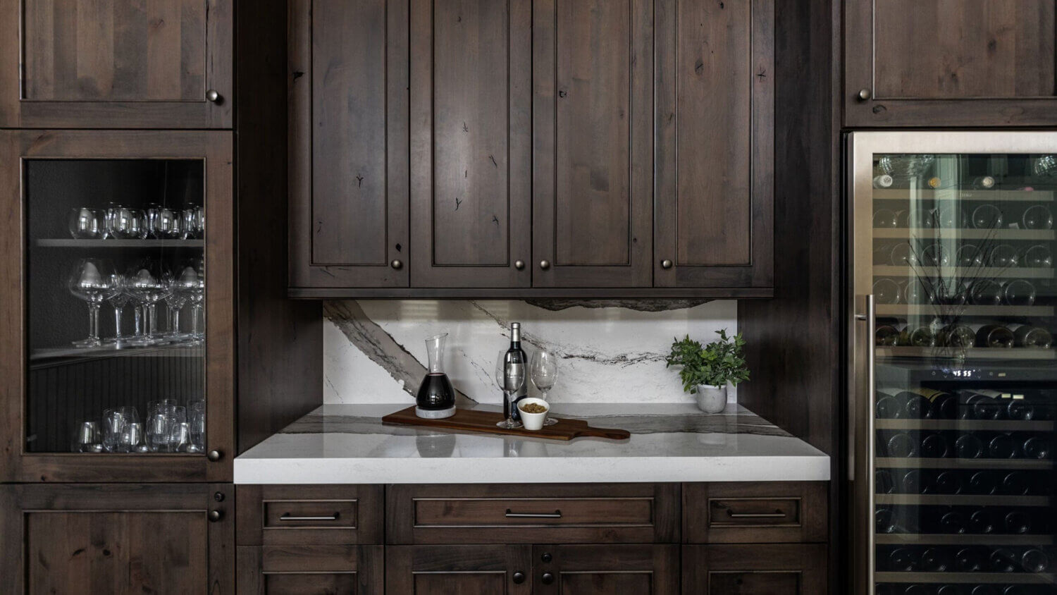 The beverage center wall of knotty alder cabinets in the dining room featuring a tall wine fridge and lots of storage.