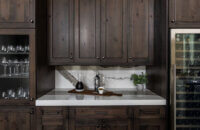 The beverage center wall of knotty alder cabinets in the dining room featuring a tall wine fridge and lots of storage.