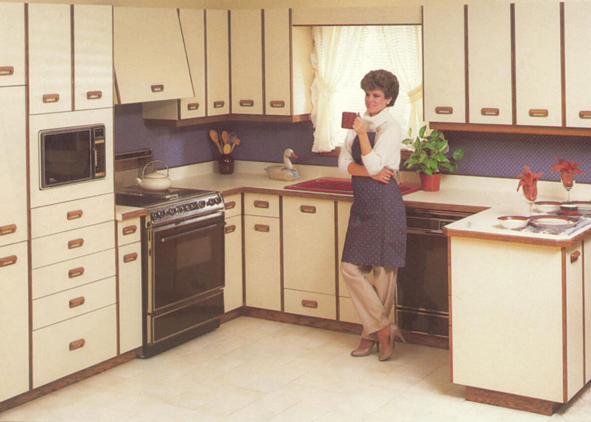 A modern kitchen during the 1980s featuring antique, off-white painted cabinets.