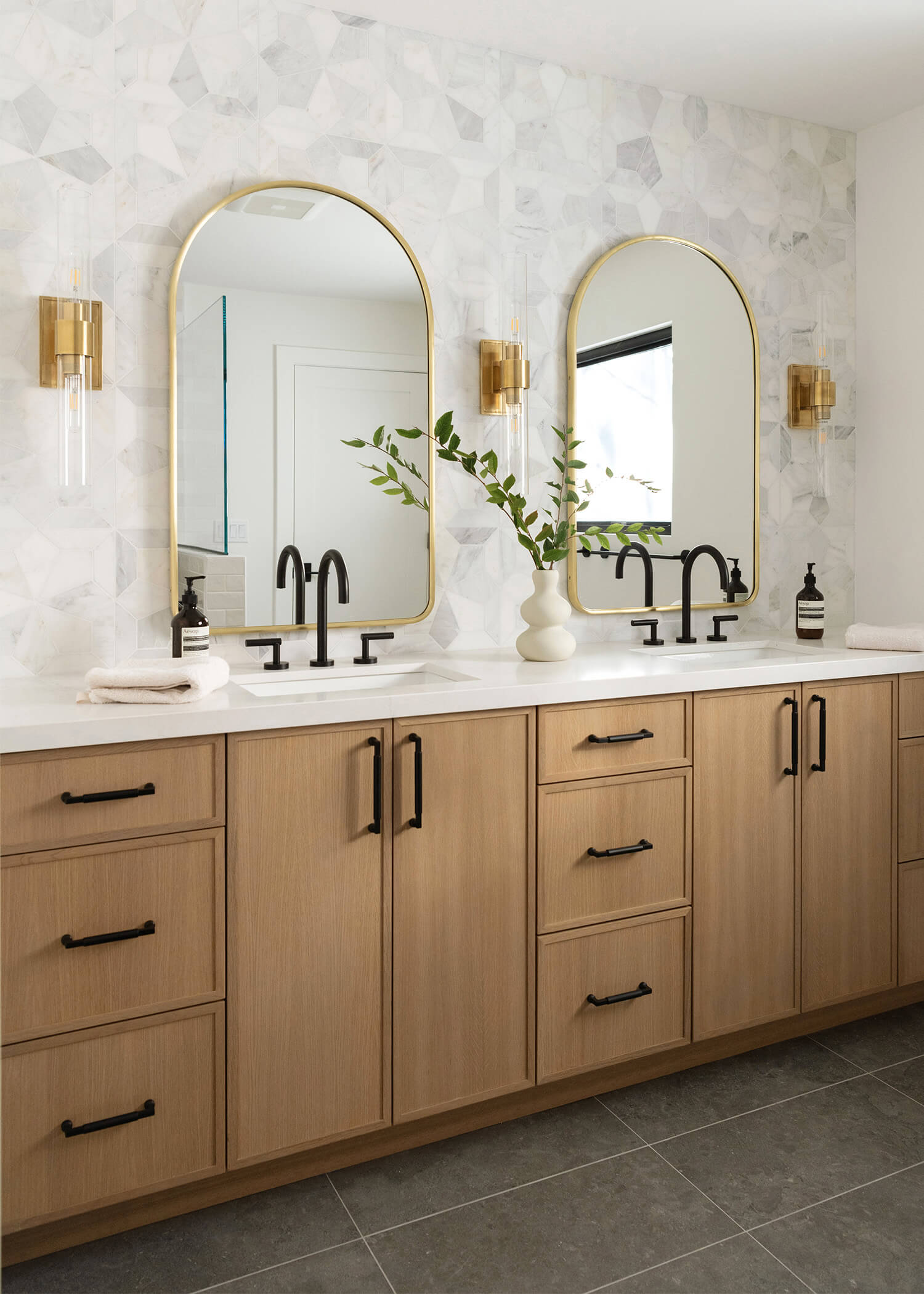 A luxurious and modern double sink vanity featuring skinny shaker cabinet doors in a warm, light stained finish on Quartersawn white oak.